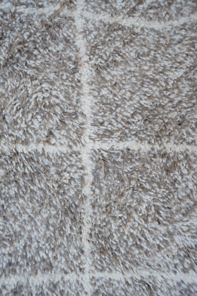 Tapis berbère aux tons beige et crème avec des motifs en losanges et une texture douce et shaggy.