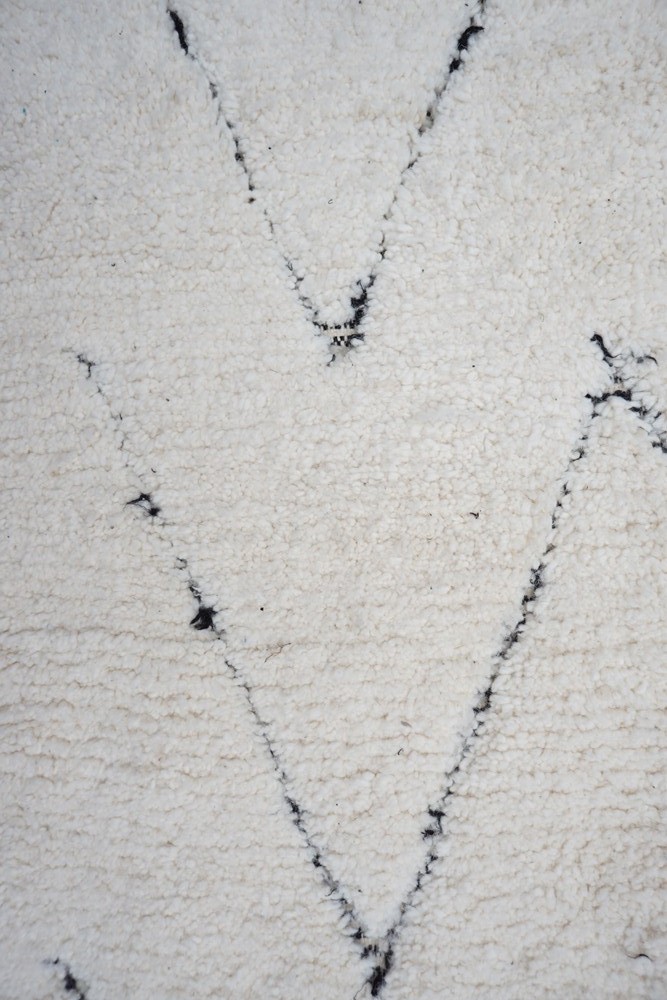 Tapis berbère en couleur crème avec motifs géométriques noirs et textures douces.