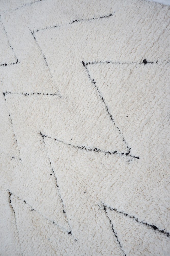 Tapis berbère en laine crème avec motifs en zigzag noir, ajoutant une touche moderne et élégante à votre décor.