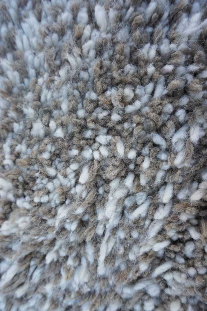Ein Teppich im Shag-Stil, in Grau- und Weißtönen, mit einer strukturierten Musterung und weichen Schlingen.