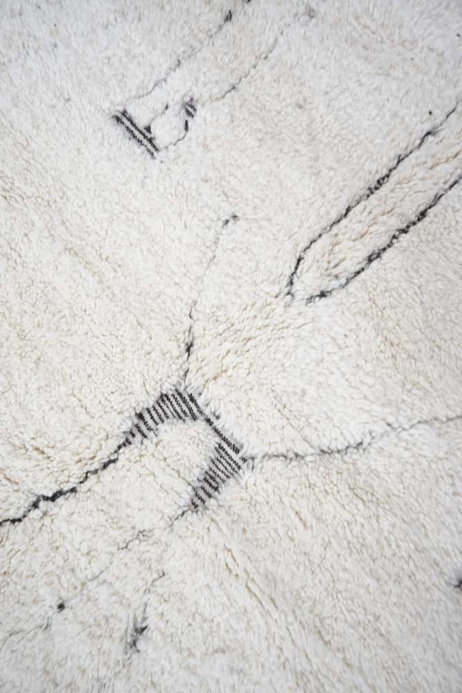 Tapis berbère en laine, motif géométrique noir sur fond blanc, ajoutant une touche moderne et chaleureuse à votre intérieur.