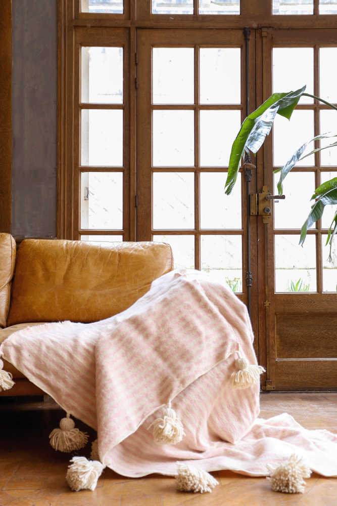 Manta bereber con borlas blancas y rayas rosas de lana, hecha a mano en Marruecos.