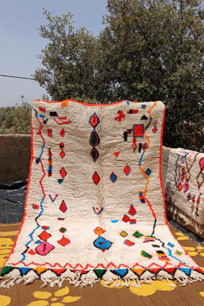 Zeer groot wit Berber Azilal-tapijt met ruiten en zigzags in roze, groen, blauw, geel en een oranje rand.