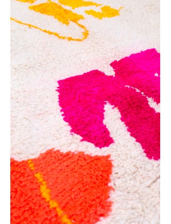 Tapis berb&egrave;re color&eacute; avec des motifs floraux en rose vif, jaune et orange sur fond cr&eacute;meux.