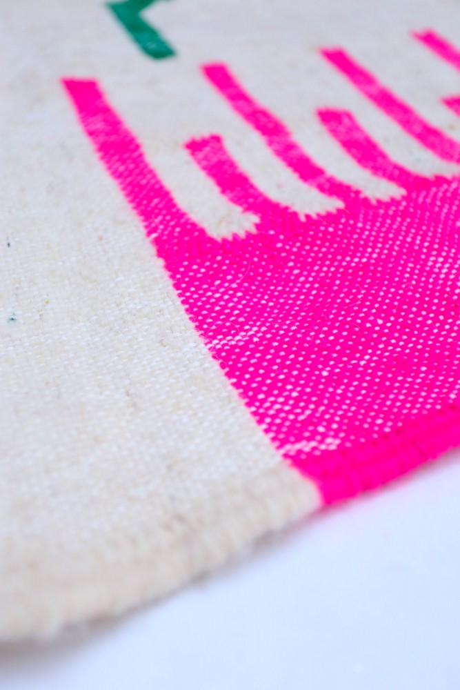 Tapis berbère coloré avec des motifs modernes en rose vif et blanc sur fond clair, idéal pour une décoration contemporaine.
