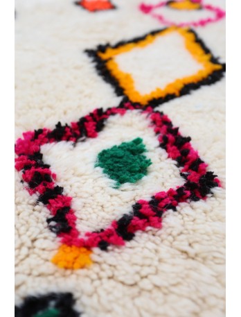 Tapis berb&egrave;re aux motifs g&eacute;om&eacute;triques color&eacute;s, domin&eacute; par le beige, le rose, le vert et le noir.