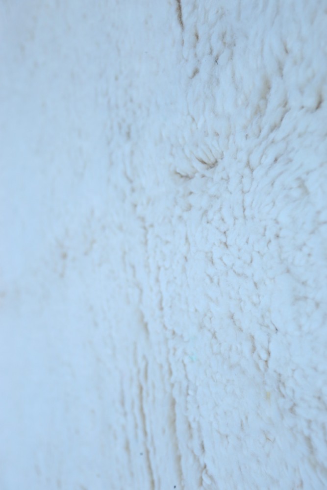 Tapis berbère en laine blanche, au design textured, aux motifs subtils, apportant chaleur et élégance à votre intérieur.