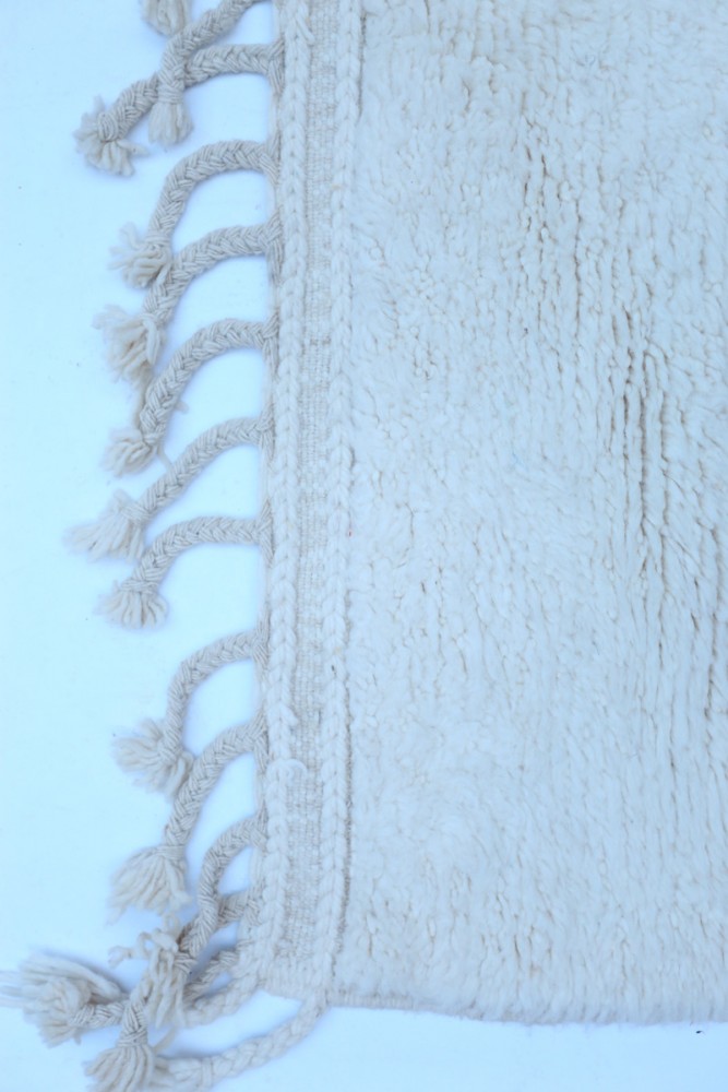 Tapis berbère en laine beige, doux, avec franges torsadées et texture fluffy pour un style chaleureux et intérieur contemporain.