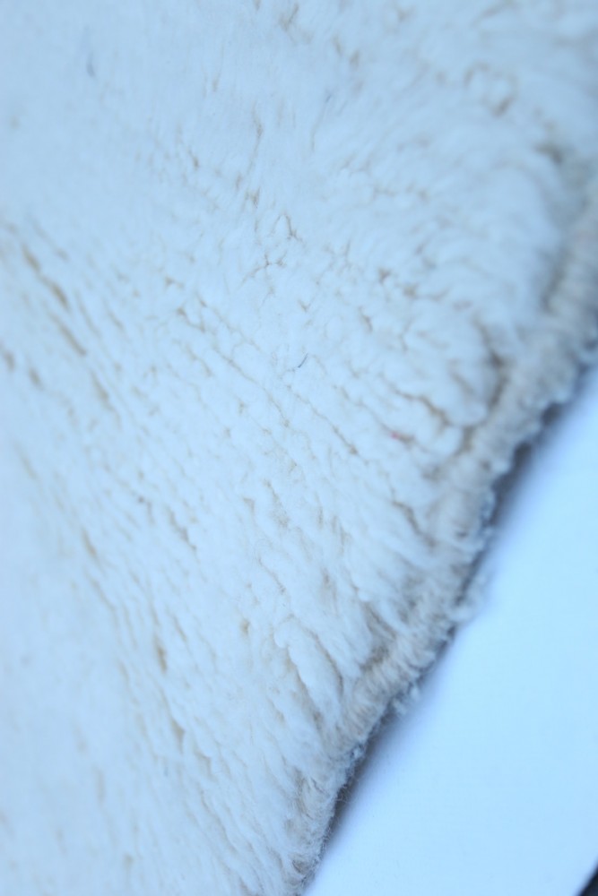 Tapis berbère en laine, de couleur crème, avec un design doux et texturé.