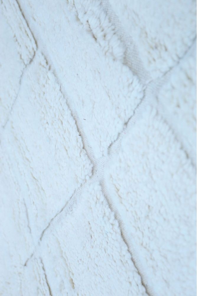 Tapis berbère doux en blanc, avec des motifs géométriques et texture tuftée.