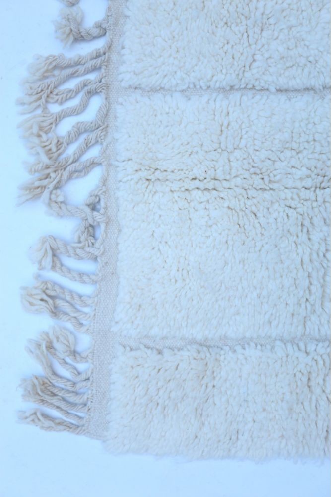 Tapis berbère en laine beige avec franges, au style chic et contemporain.