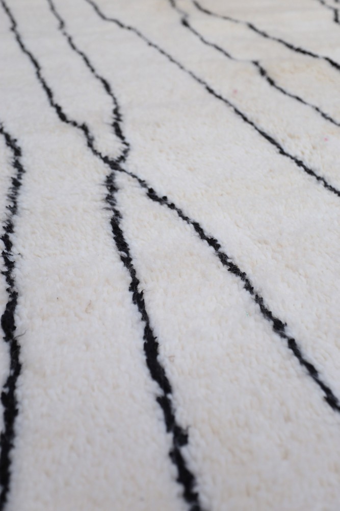 Tapis berbère en laine, blanc cassé avec des lignes noires, au design contemporain et minimaliste.