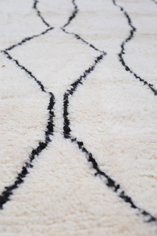 Tapis berbère blanc avec des motifs géométriques noirs, apportant un style moderne et chaleureux à toute décor.