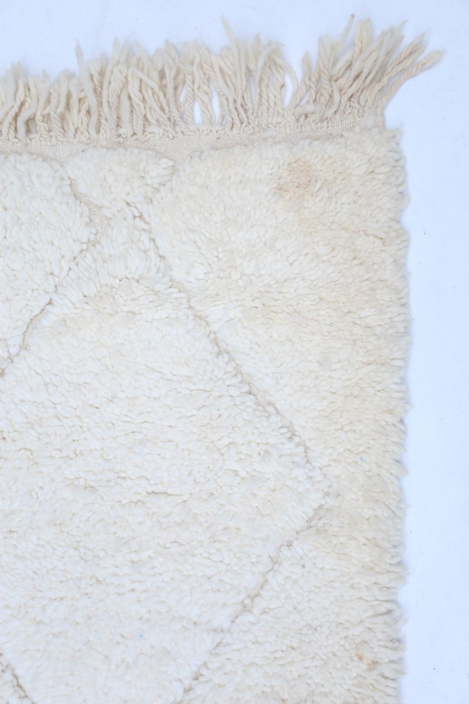 Tapis berbère douillet en laine, couleurs neutres, motifs géométriques en losanges et finition à franges.
