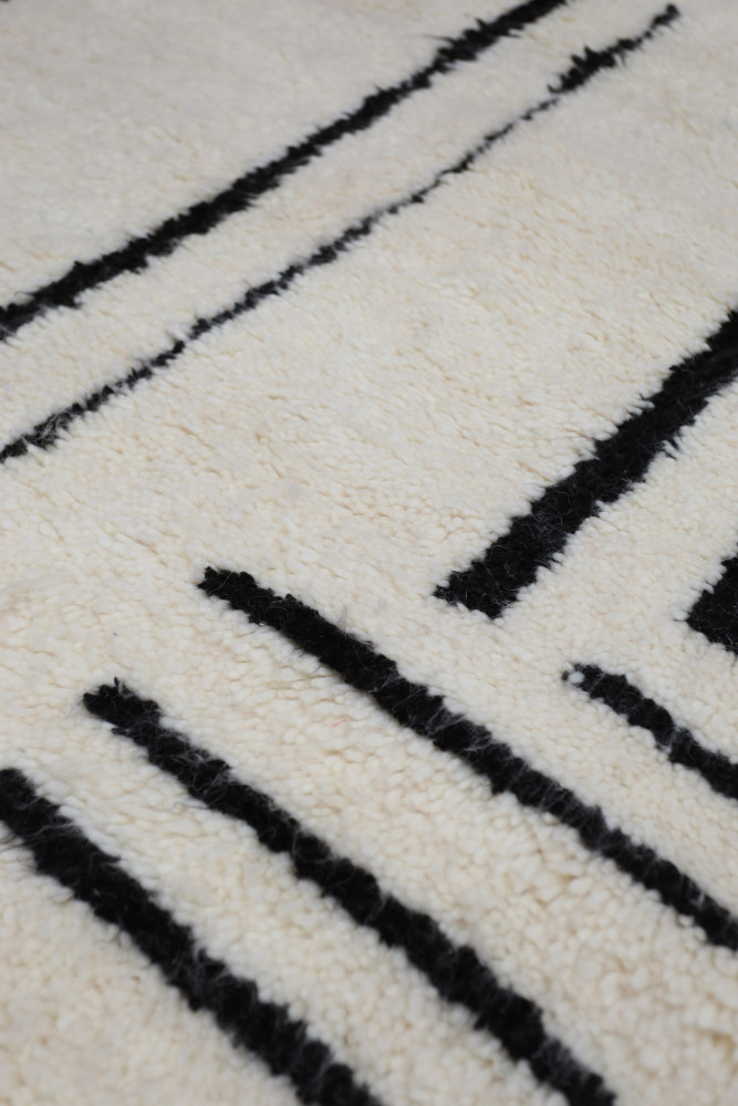Tapis moderne beige avec des motifs noirs en lignes, apportant une touche élégante et graphique à votre décoration.