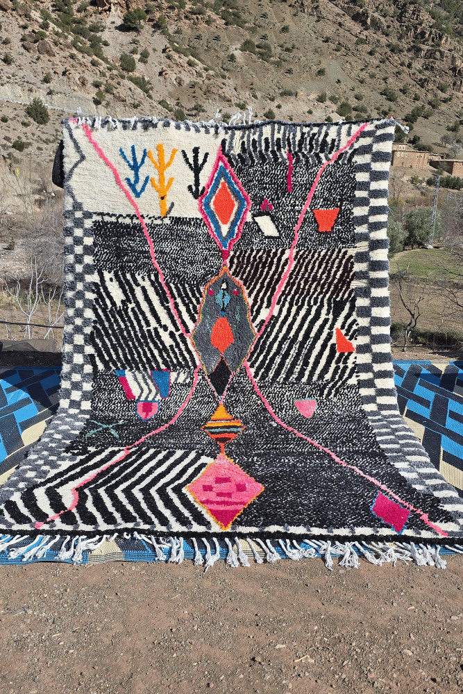 Tapis berbère aux motifs géométriques, couleurs vives comme le rose et noir, avec un design dynamique et moderne.
