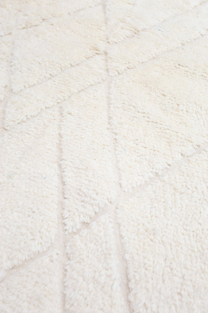 Tapis moderne en laine crème avec motifs géométriques en relief, apportant chaleur et élégance à votre intérieur.