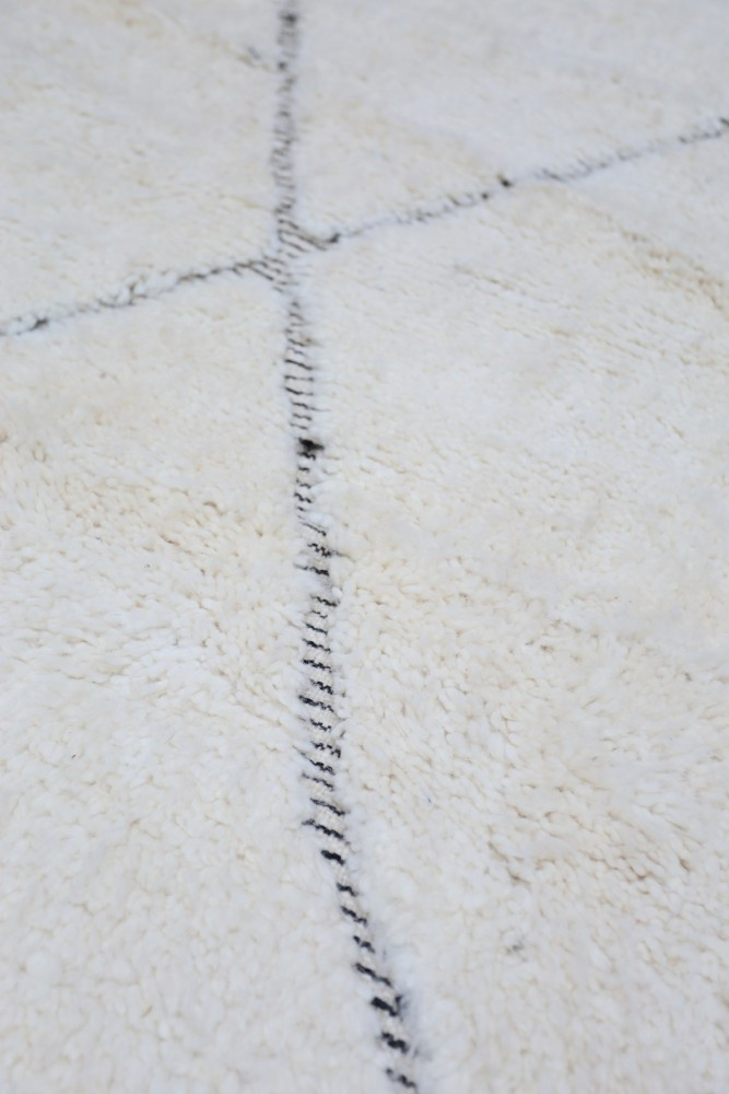 Tapis berbère doux en blanc crémeux avec des motifs géométriques noirs.