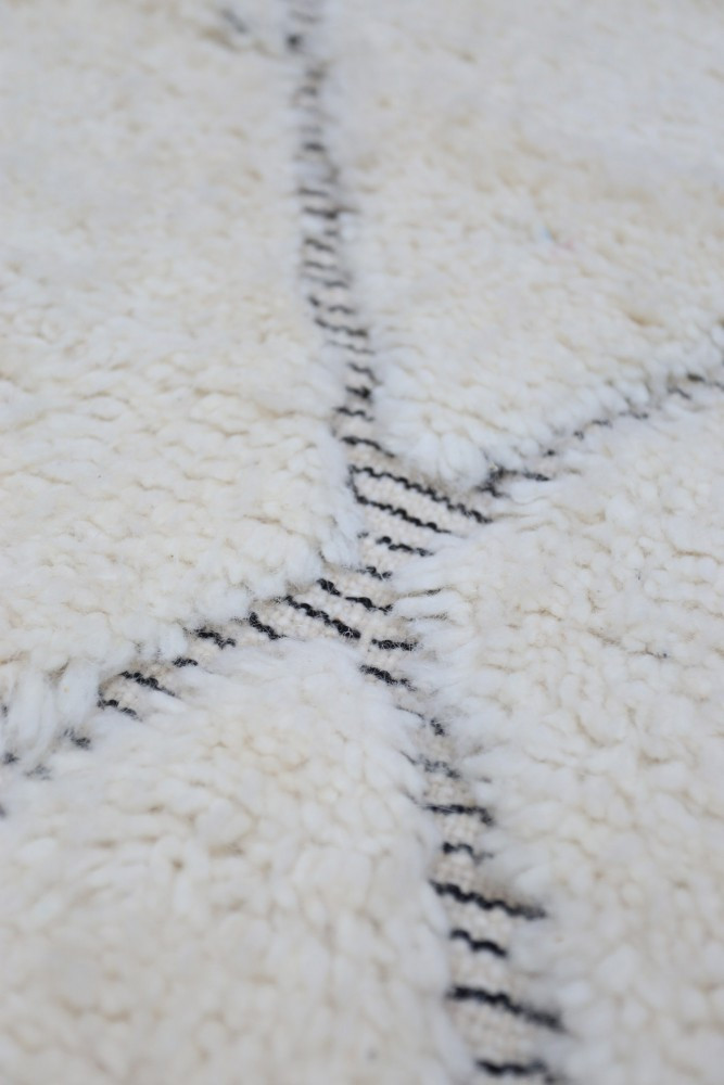 Tapis berbère en laine avec motifs géométriques noirs sur fond crème, idéal pour une décoration moderne et chaleureuse.