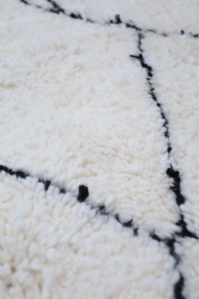 Tapis berbère blanc avec motifs géométriques en noir offrant une texture douce et confortable.