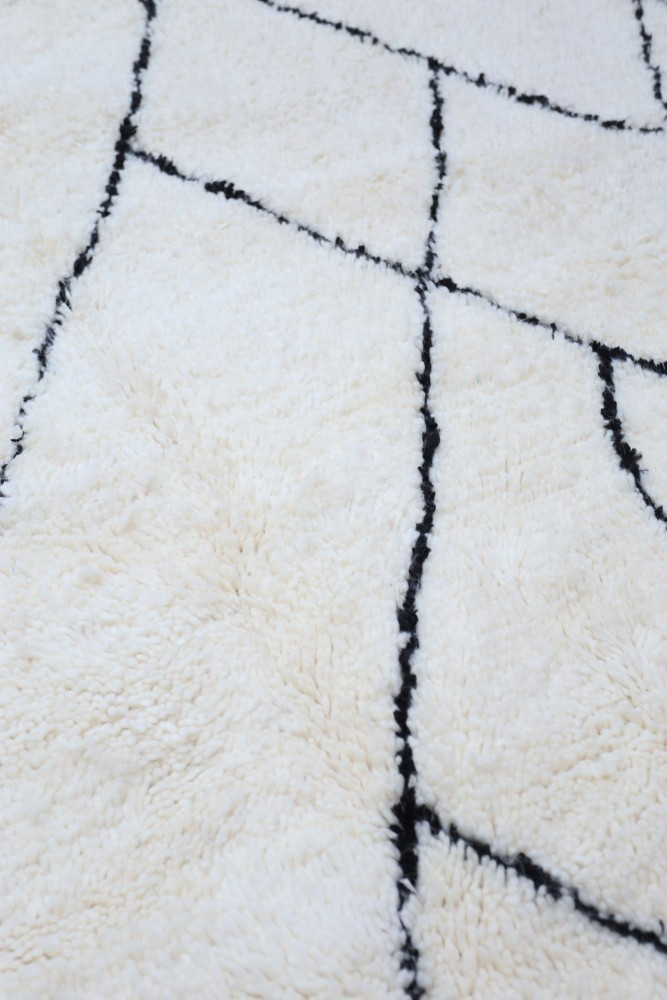 Tapis en fausse fourrure beige avec motifs géométriques noirs, ajouté une touche moderne et chaleureuse à votre intérieur.
