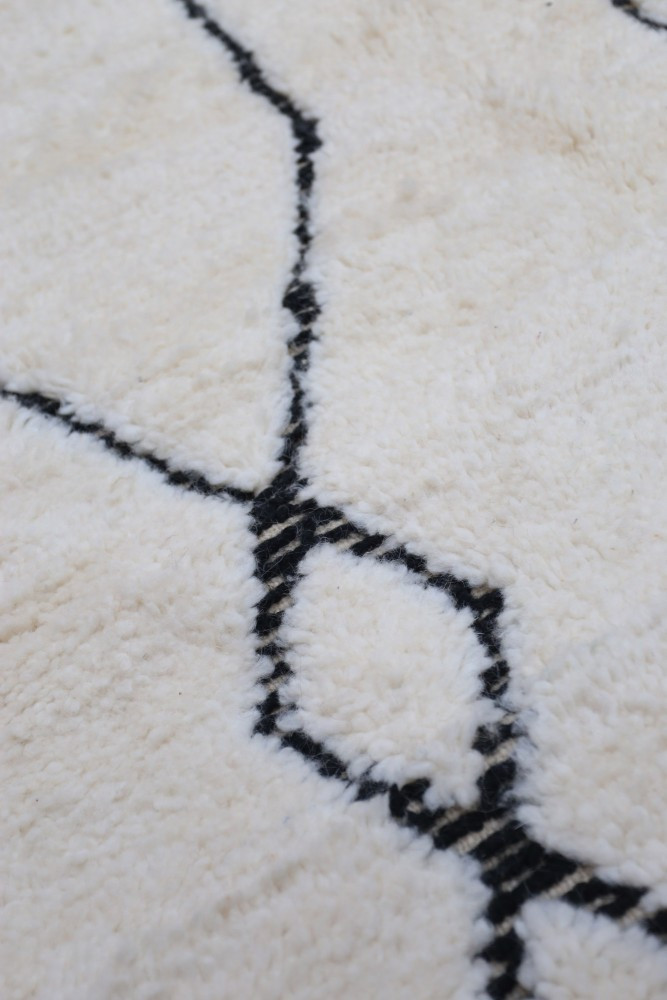 Tapis berbère crème avec motifs géométriques noirs pour un intérieur moderne et élégant.