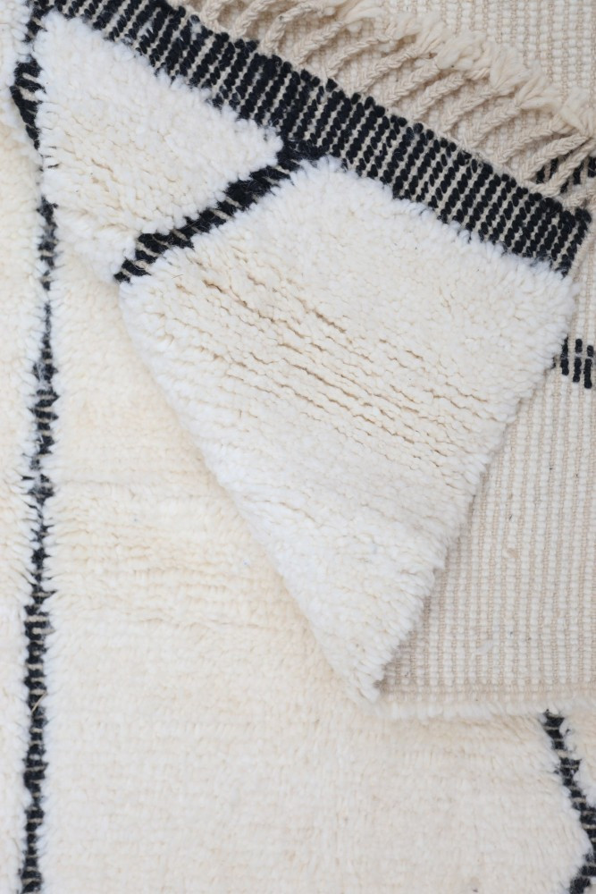 Tapis berbère en blanc crémeux avec motifs géométriques noirs pour une ambiance moderne et chaleureuse.