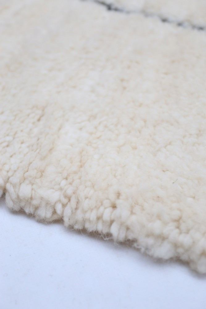 Tapis en laine à motifs subtils, couleur crème, apportant chaleur et douceur à votre intérieur.