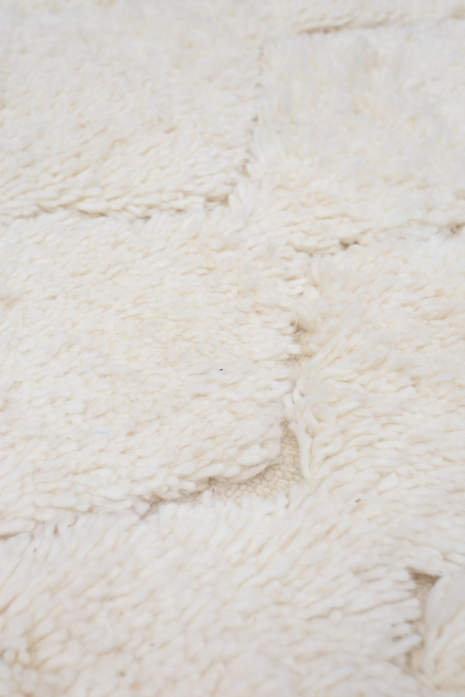 Tapis moelleux en blanc éclatant, avec un motif texturé et doux, idéal pour un décor chaleureux et moderne.