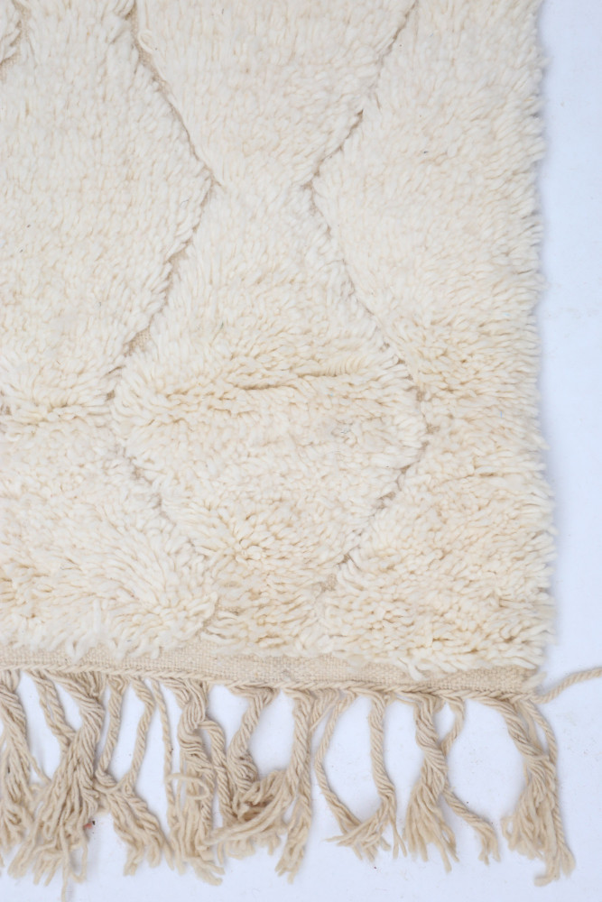 Tapis berbère beige avec un motif en losanges et des franges, ajoutant chaleur et élégance à votre intérieur.