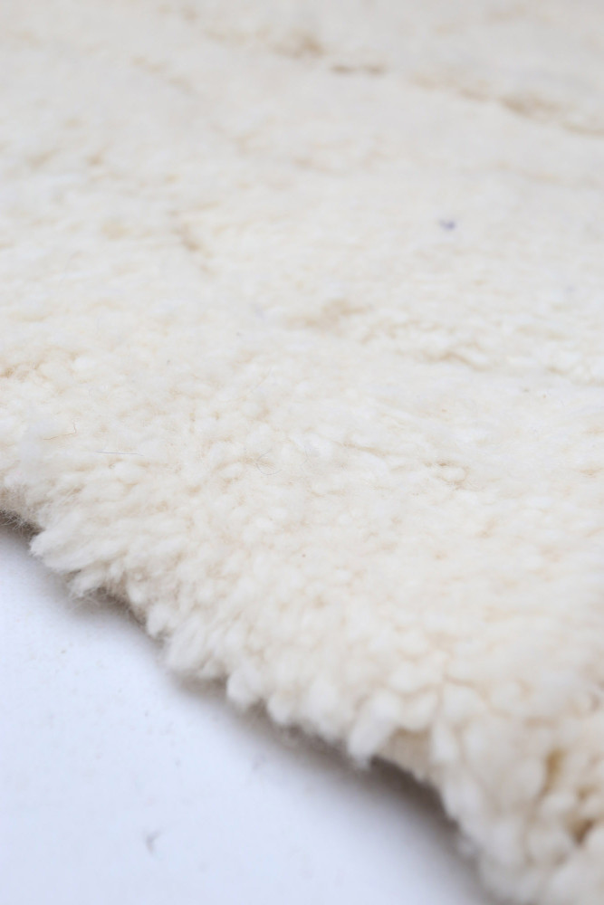 Tapis en laine beige au style moderne, doux au toucher avec un aspect texturé et élégant.