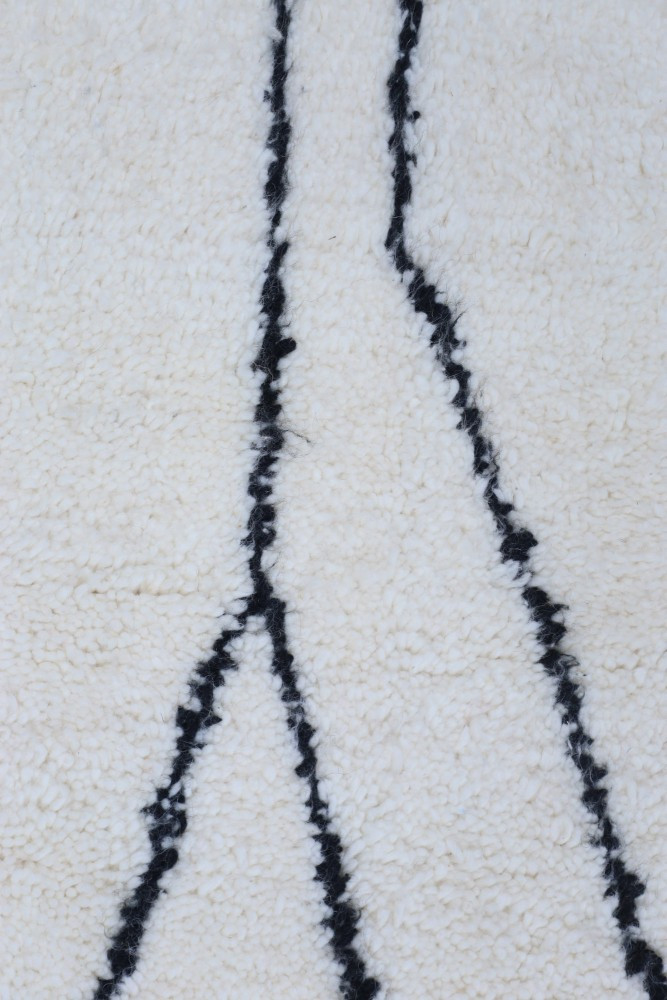 Tapis berbère beige à motifs noirs, évoquant un style contemporain et chaleureux.