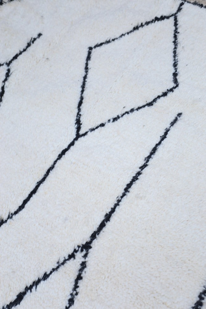 Tapis berbère blanc avec motifs géométriques noirs, ajoutant une touche moderne et élégante à votre intérieur.