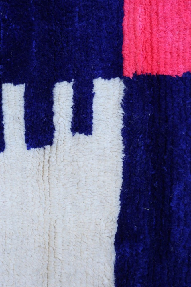 Tapis berbère aux motifs géométriques en bleu, rose et crème, ajoutant une touche moderne à votre intérieur.