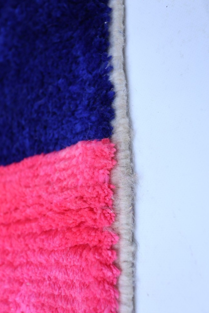 Tapis berbère aux couleurs vives, bleu et rose, avec un design moderne et texturé.