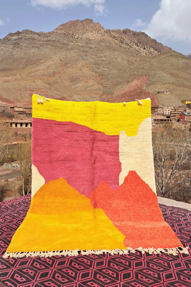 Tapis berbère aux couleurs vives avec motifs géométriques en jaune, rose et orange, idéal pour un intérieur moderne.