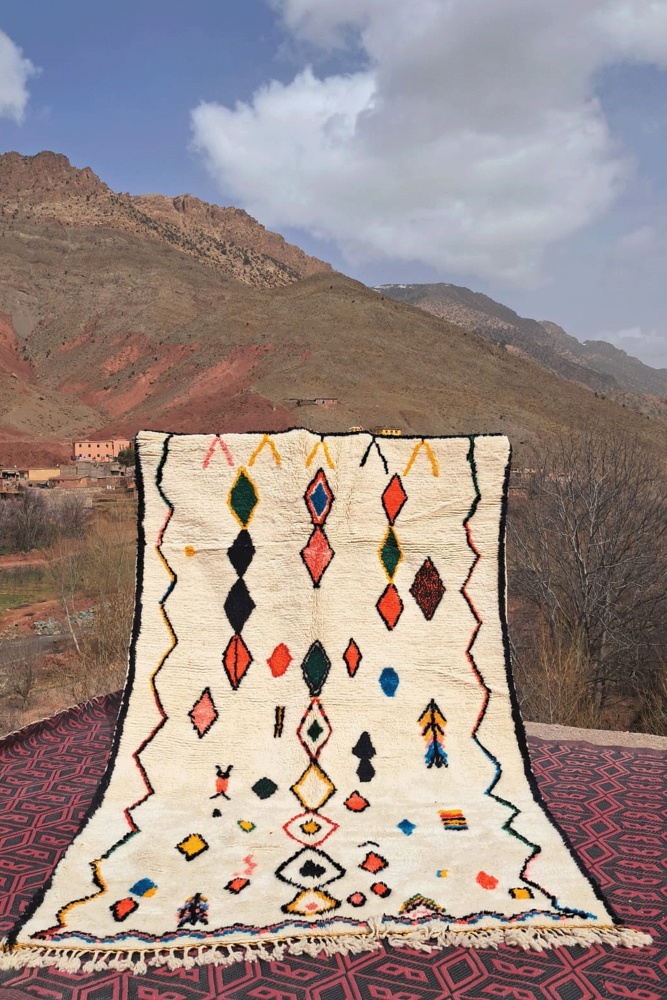 Tapis berbère aux motifs géométriques colorés, dominé par des tons neutres et des accents vifs, idéale pour un décor bohème.