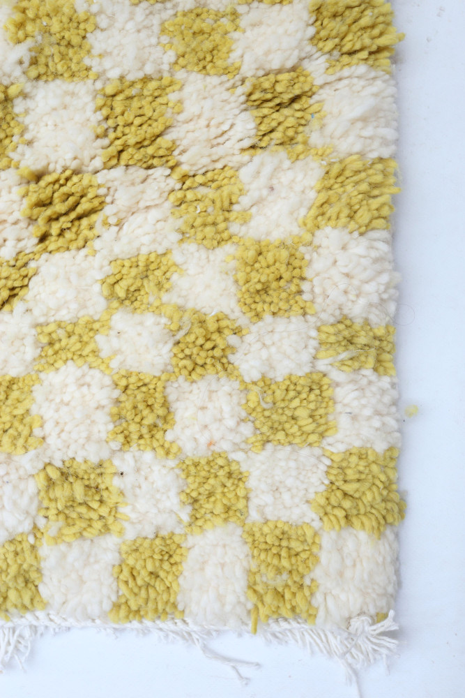 Tapis berbère à motifs en damier, couleurs jaune vif et blanc, avec une texture douce et chaleureuse.