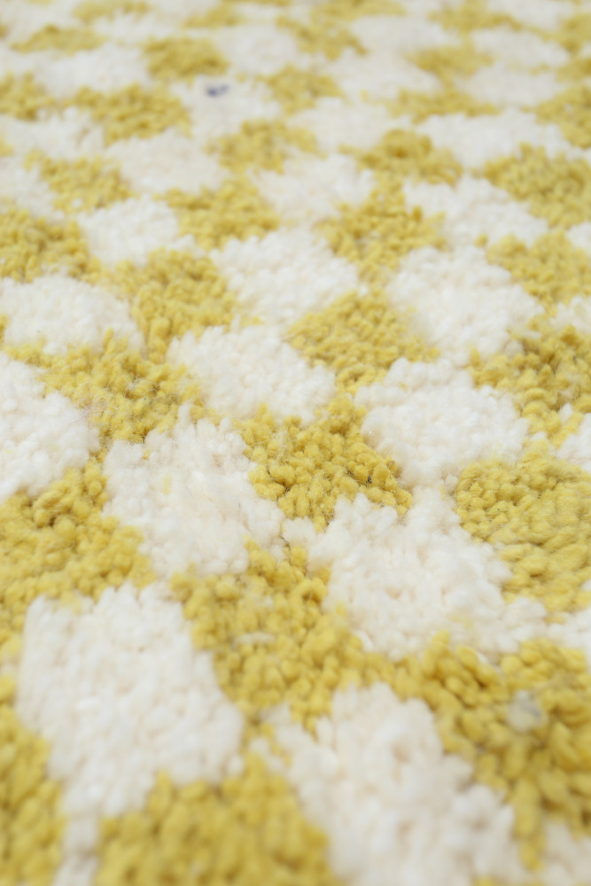 Tapis berbère à motifs losanges jaunes et blancs, ajoutant une touche chaleureuse et moderne à tout intérieur.