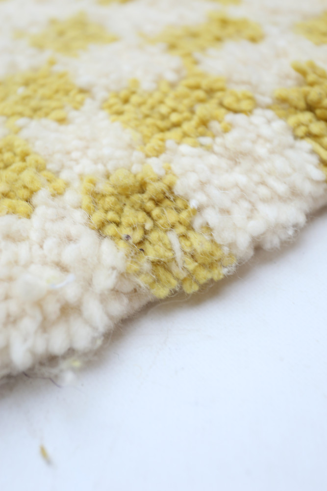 Tapis berbère aux motifs géométriques dans des teintes de jaune et crème, ajoutant une touche chaleureuse à votre intérieur.