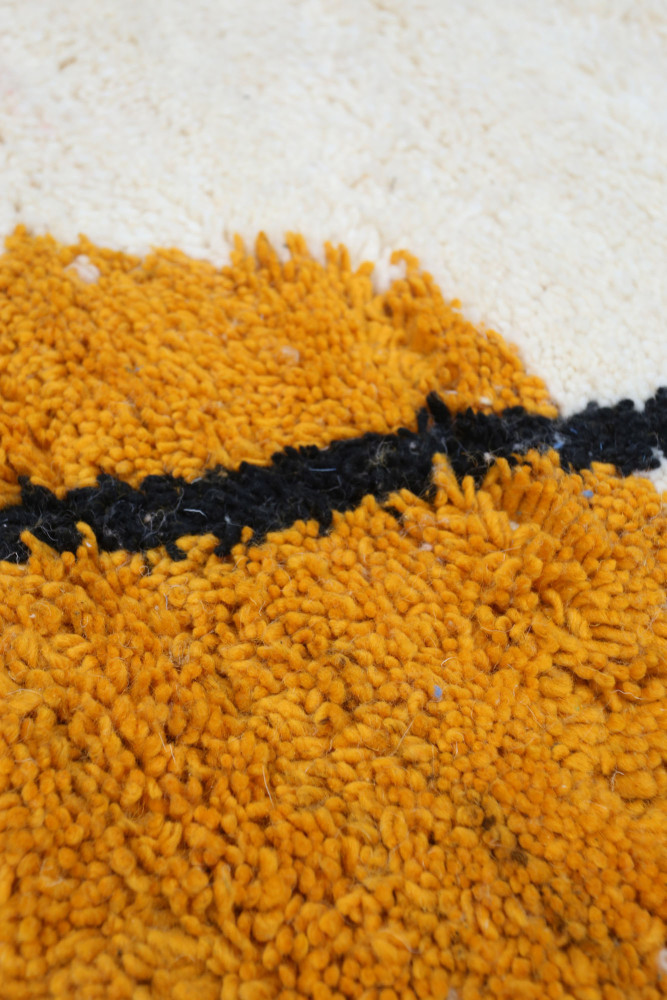 Tapis berbère aux motifs géométriques, dominé par des teintes orange, noir et crème, parfait pour ajouter une touche chaleureuse