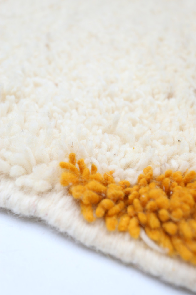Tapis berbère blanc avec des motifs texturés en jaune, ajoutant une touche chaleureuse et artisanale à votre intérieur.