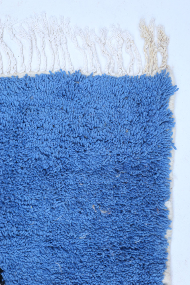 Tapis berbère en bleu vif, fabriqué en laine, avec un tissage doux et des franges délicates, parfait pour un intérieur moderne.