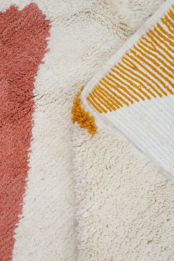 Tapis berbère aux motifs géométriques, avec des couleurs beige, rose et jaune, ajoutant une touche moderne et chaleureuse.