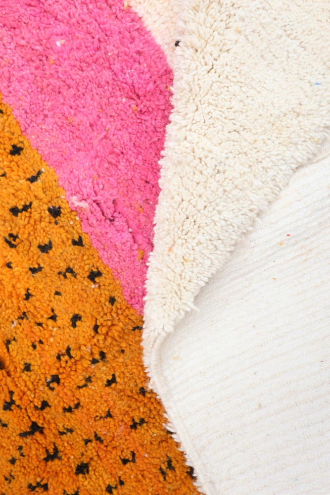 Tapis berbère contemporain aux couleurs vives rose, orange et crème avec motifs géométriques et texture moelleuse.