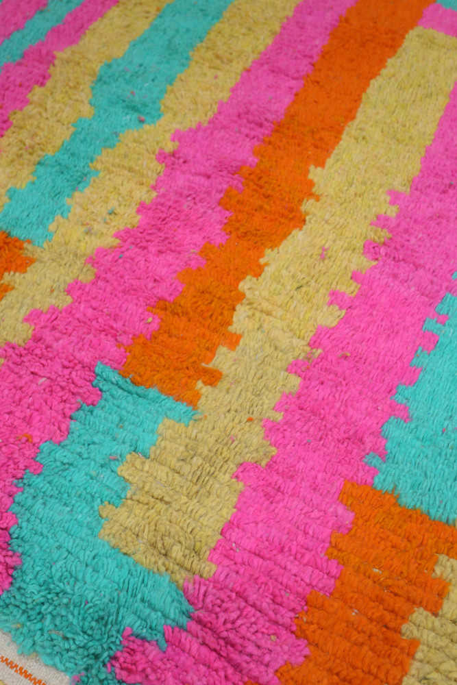 Tapis berbère coloré avec des motifs géométriques en rose, turquoise, orange et jaune, apportant une touche moderne à votre déco