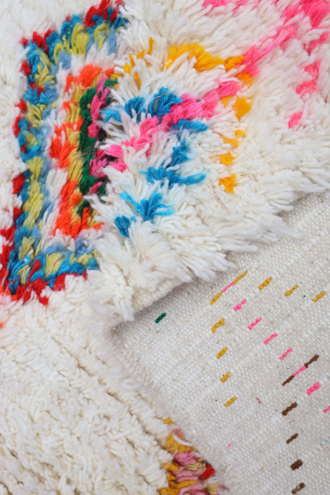 Tapis berbère multicolore avec motifs géométriques sur fond crémeux, alliant modernité et tradition.