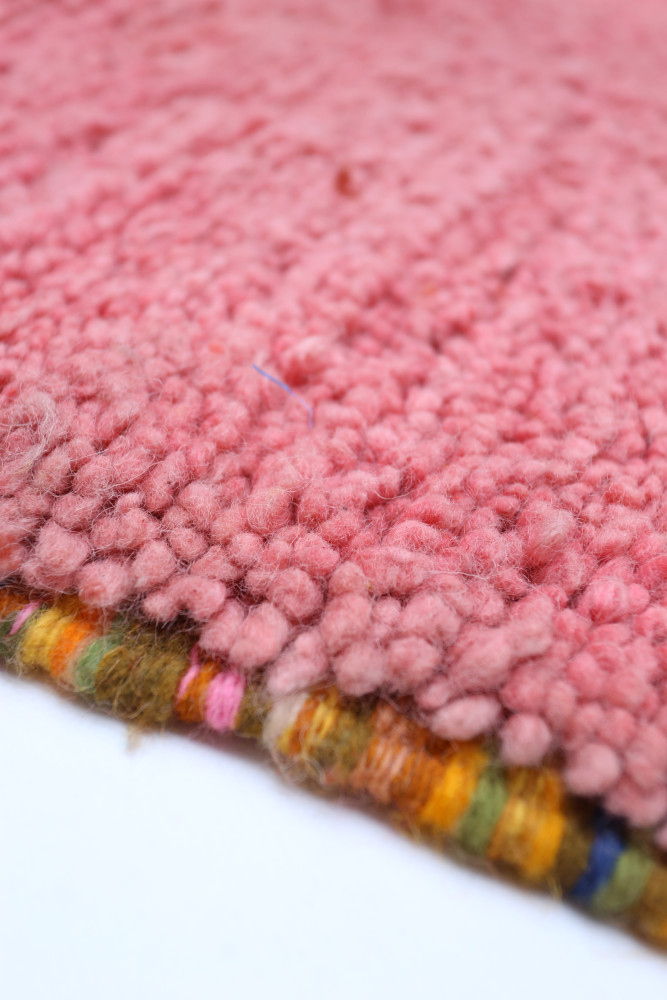 Tapis berbère en laine rose avec des motifs colorés et une texture douce, ajoutant une touche artisanale à votre intérieur.