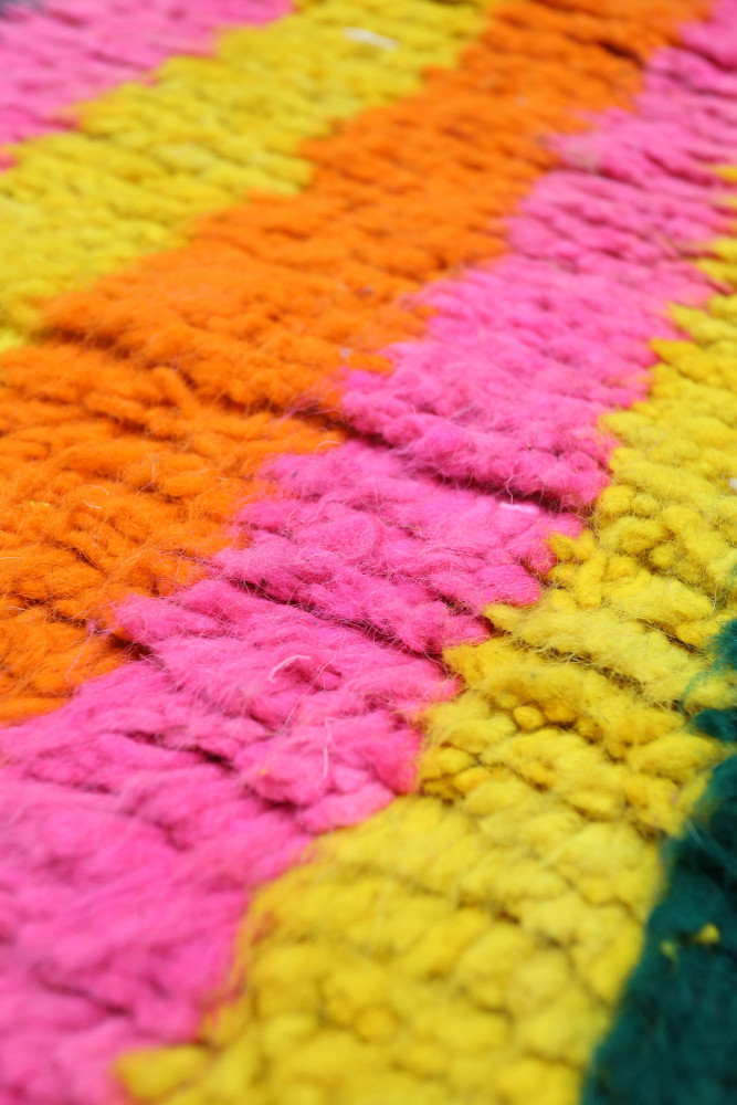 Tapis berbère aux couleurs vives avec des rayures rose, orange, jaune et vert, offrant un style moderne et joyeux.