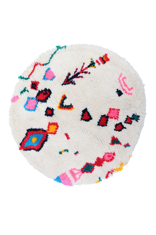 Tapis berbère rond aux motifs colorés, dominé par des tons blancs, roses, bleus et noirs pour une ambiance chaleureuse.